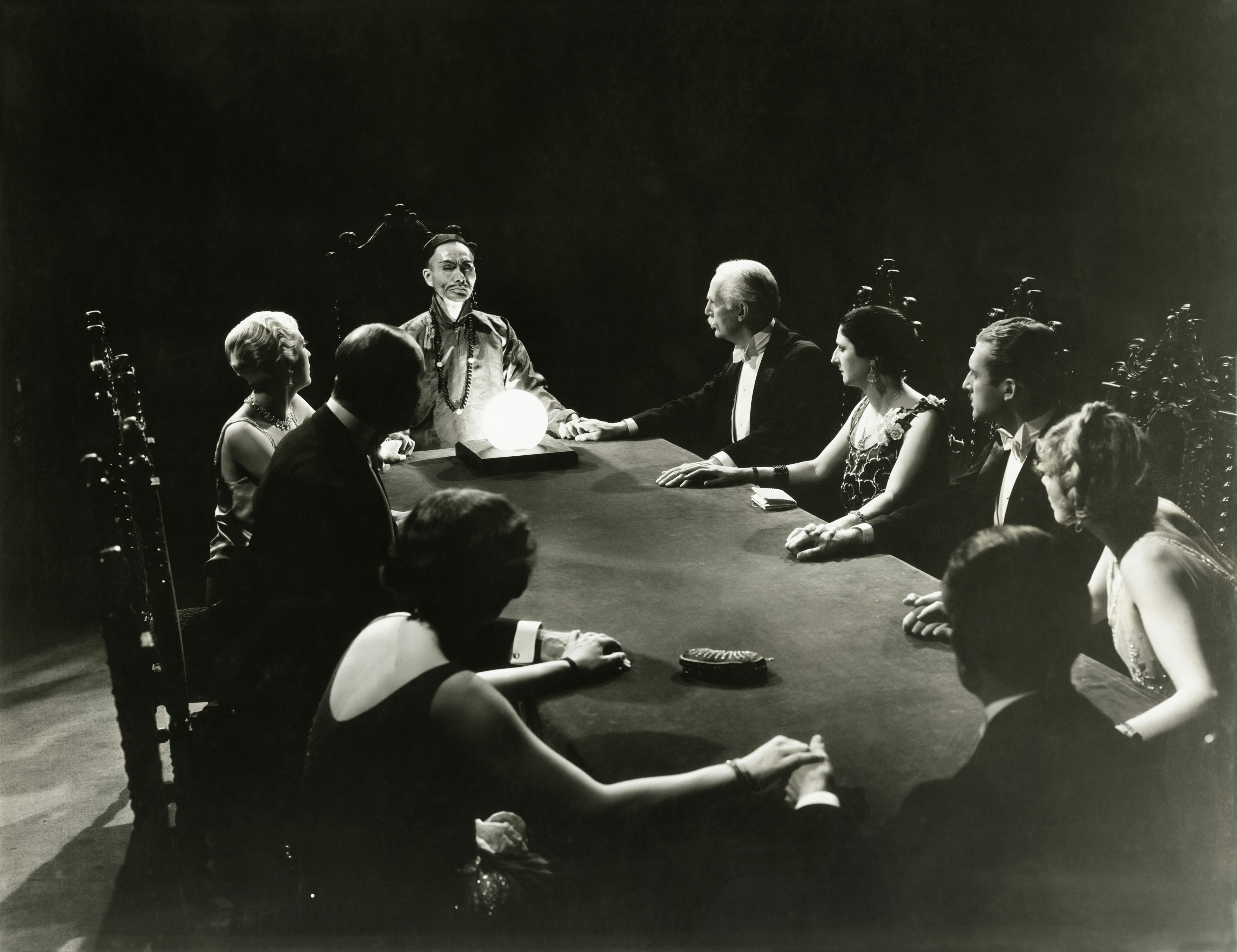 A black and white photograph of a group of people performing a seance.