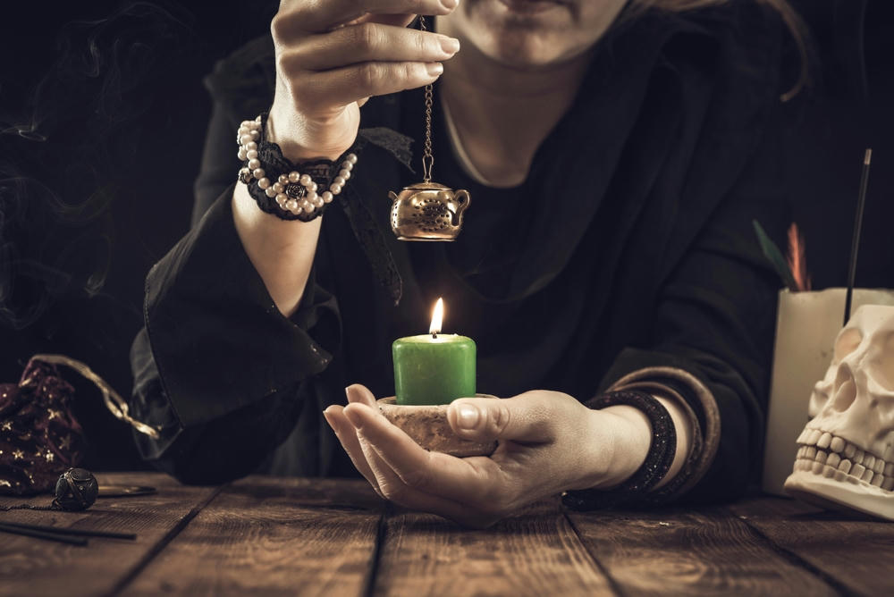 Fortune teller or oracle with items and a lit candle. Psychic readings and clairvoyance concept.