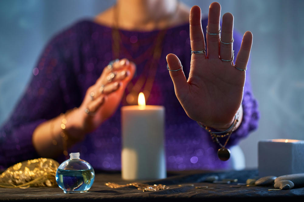 Fortune teller woman using burning candle flame for spells, witchcraft, divination and fortune telling.