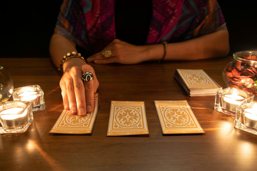 women pulling a tarot card with candles
