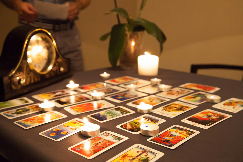 Mystic fortune-telling with fired candles and playing cards on a dark background.