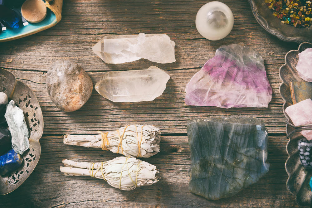 Natural gemstones, white sage and incense on a wooden board.