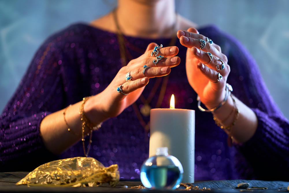 A woman using burning candle flame for spells, witchcraft, divination and fortune telling.