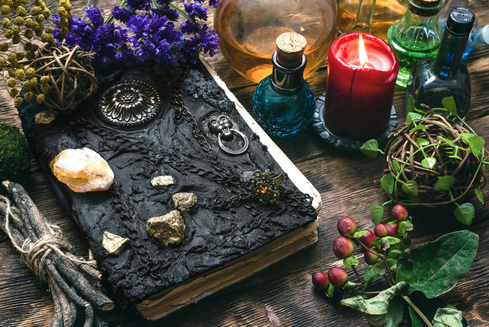 Spellbook, magic potions and other various witchcraft accessories on the wizard table background.