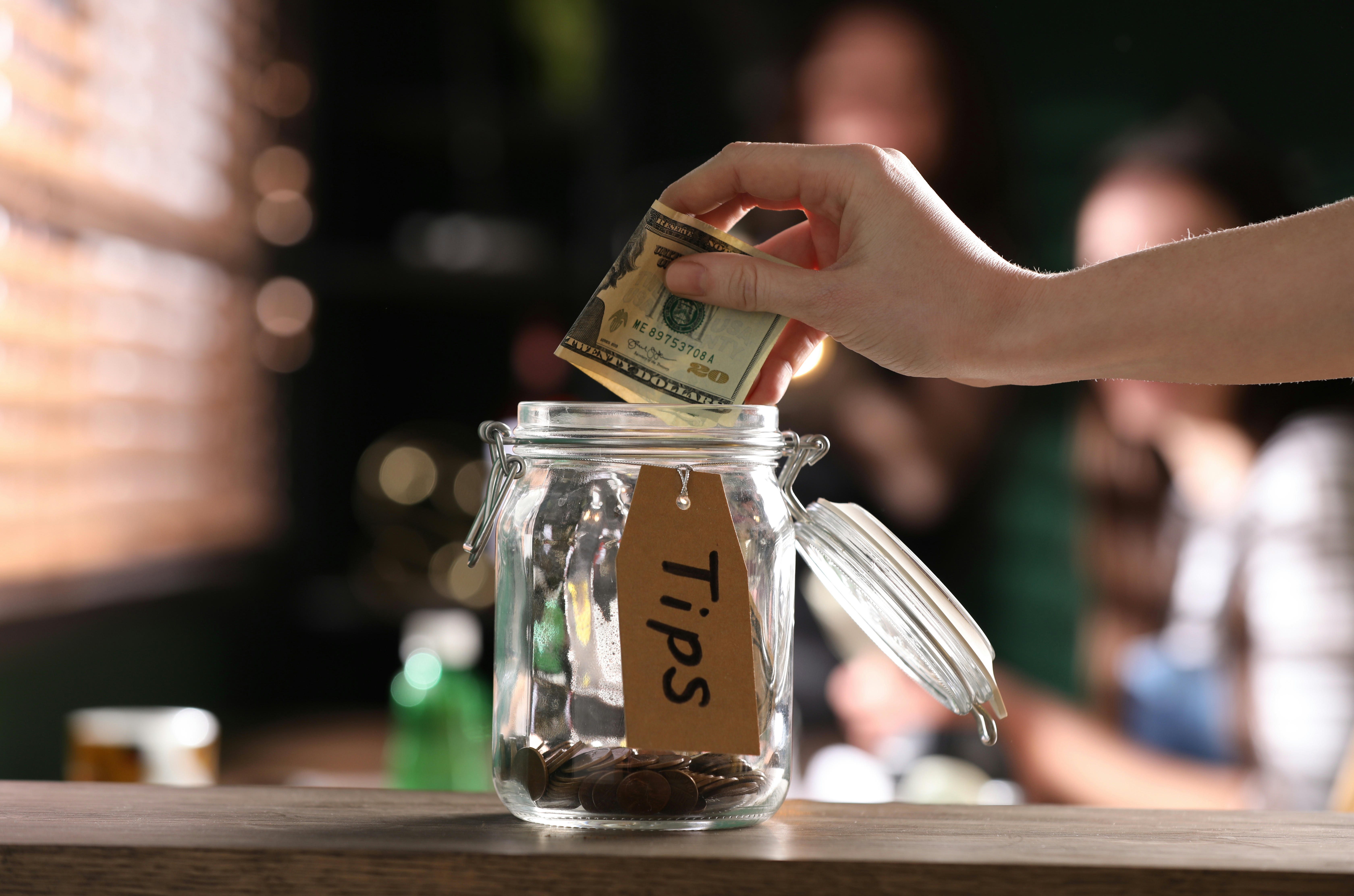 An image of a tips jar with coins and notes in