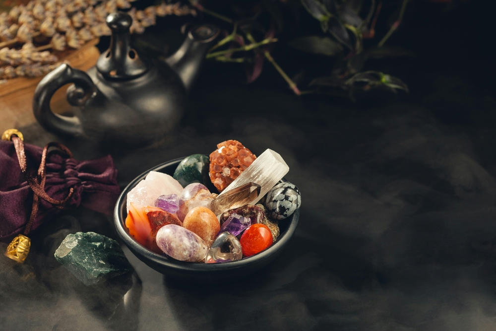 Colourful crystals and mineral stones in a black bowl shrouded in a mystical mist.