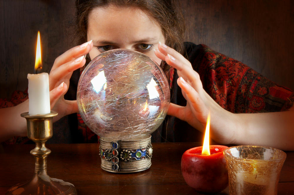 Young fortune teller in a red scarf working with her crystal ball.