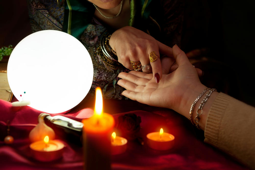 Fortune teller woman point her finger to another woman's palm, palm reading.