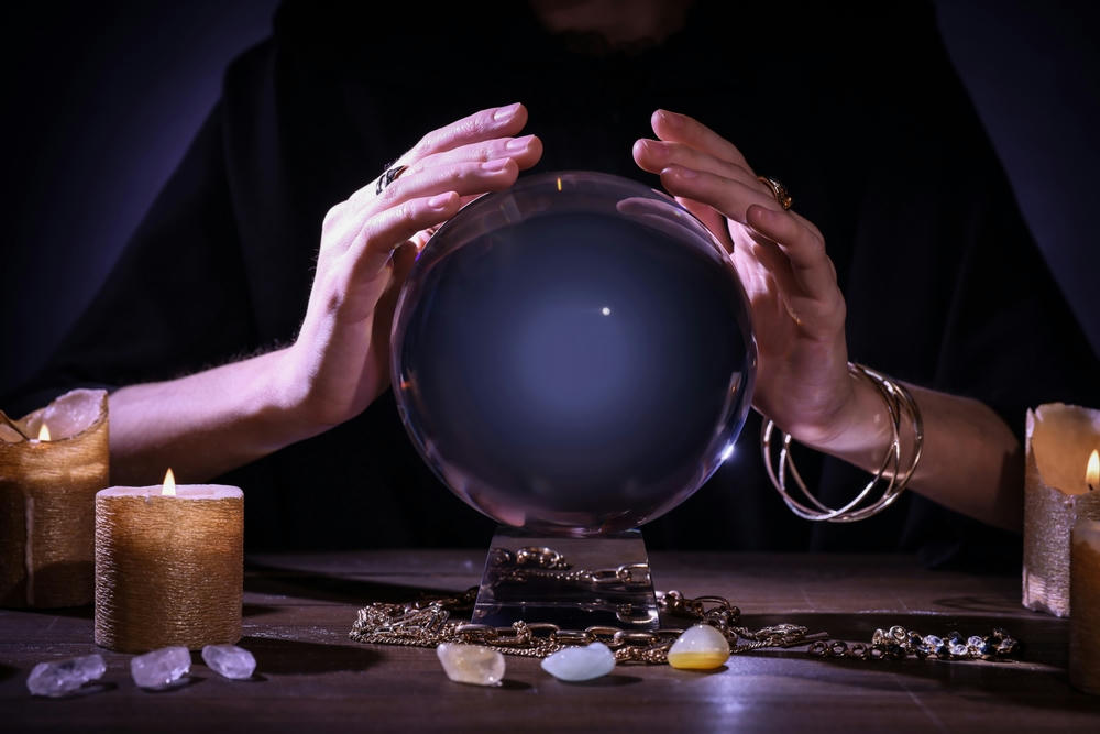 Soothsayer using a crystal ball to predict the future at a table in the darkness.