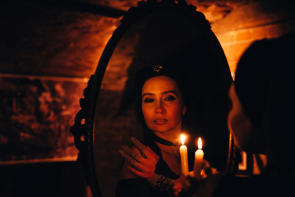 Portrait of a woman in a mirror with a candle.