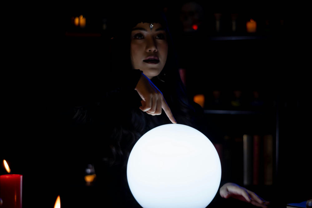 Young woman fortune teller with a glowing crystal ball to predict destiny or future.